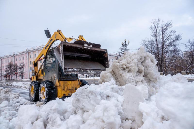 Loader clearing a big pile of snow on a city street