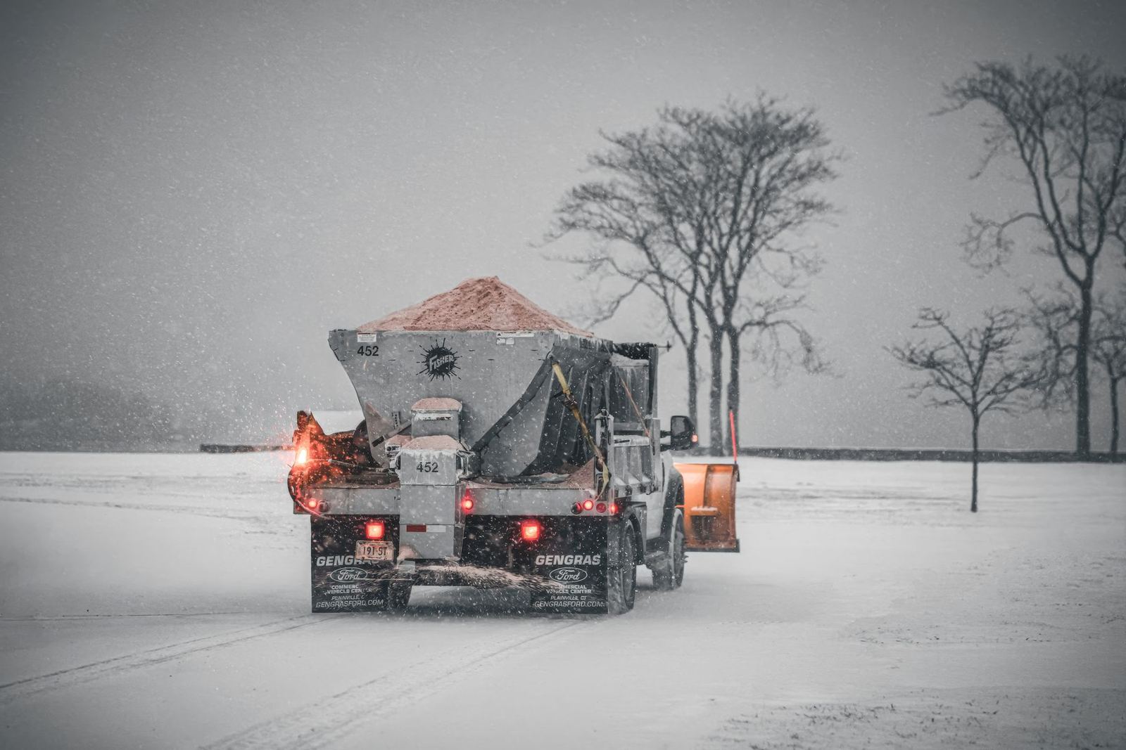 Truck spreading salt on a snowy road during a winter storm